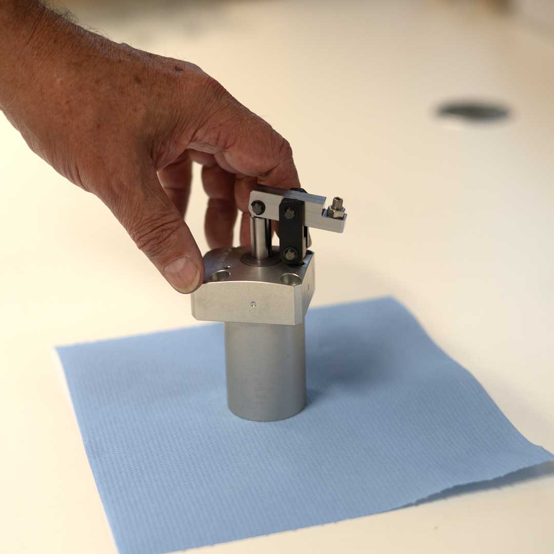 Close-up of KOSMEK clamp component inspected on a workbench.