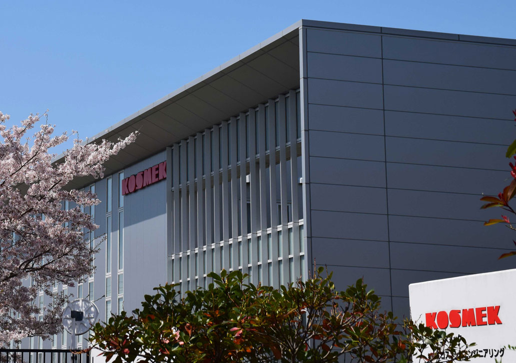 Exterior of KOSMEK headquarters in Japan with cherry blossoms and company logo, symbolizing precision, reliability, and innovation in automation technology.
