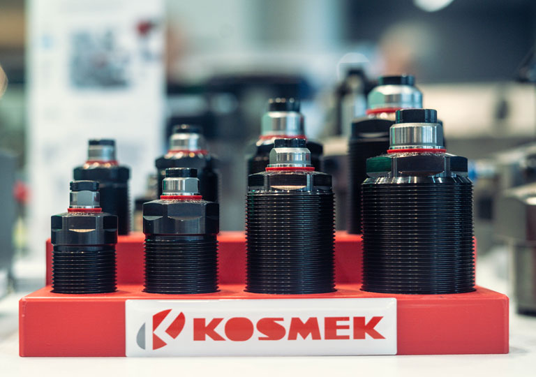 KOSMEK TNE work supports displayed on a red fixture at a trade show, showing different model sizes=